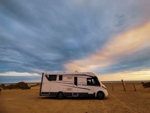 Travel vacation lifestyle with camper parked at the beach with sea view- Recreational vehicle camping car camp in the nature. Holiday concept transport big van free with ocean and sky in background