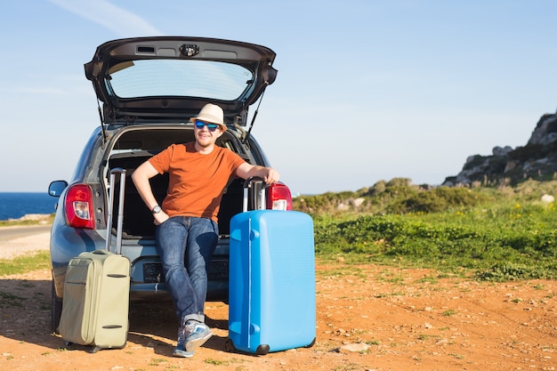 Travel, vacation, summer trip and people concept. man is going on holiday, suitcases in the trunk of a car.