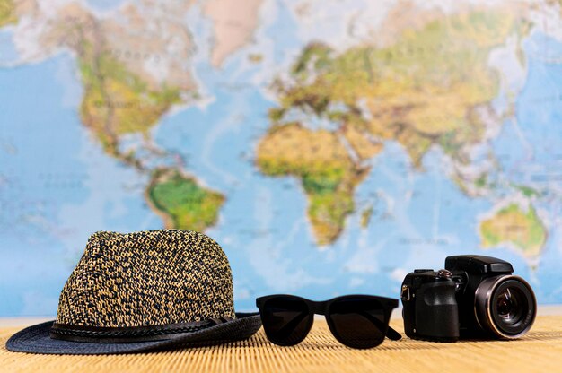 Travel and vacation theme Hat sunglasses camera Background world map