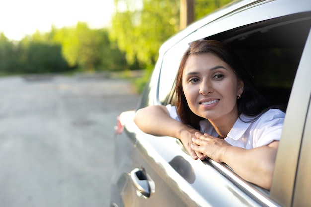 Travel vacation A young beautiful woman sits in a car and smiles looking into the distance Lifestyle