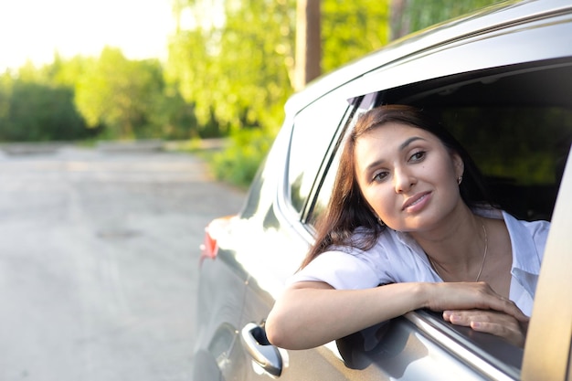 Travel vacation A young beautiful woman sits in a car and smiles looking into the distance Lifestyle