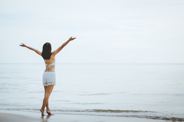 Travel woman walking on beach in sunset