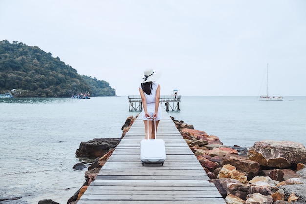 Travel woman with suitcase on beach