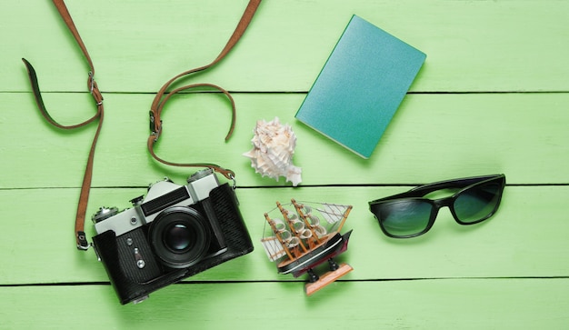 Traveler accessories, retro camera on green wooden table