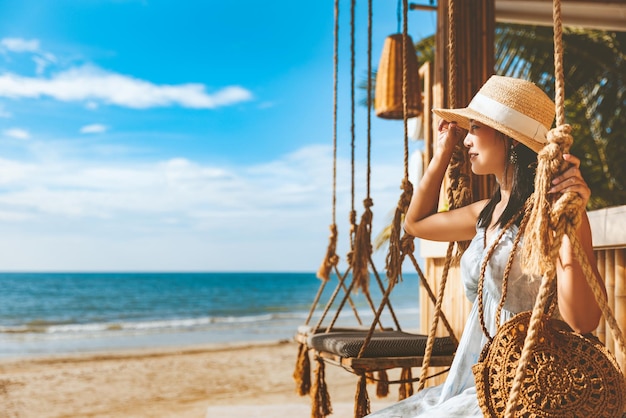 Traveler asian woman travel and relax on swing in beach cafe at Koh chang summer Thailand