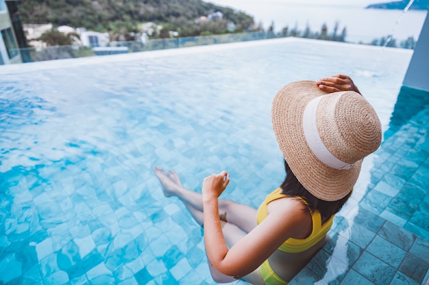 Traveler asian woman with bikini relax in luxury infinity pool resort at day in Phuket Thailand