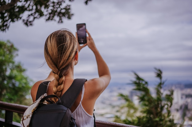 Traveler blonde backpacker woman walking taking photos from observation deck overlooking the downtown. Travel adventure in China, Tourist beautiful destination Asia, Summer holiday vacation trip