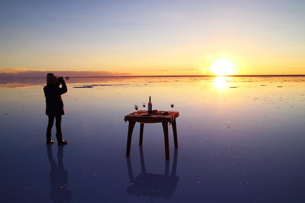 Traveler Celebrating on Mirror Effect of Salar de Uyuni at Stunning Sunset Bolivia