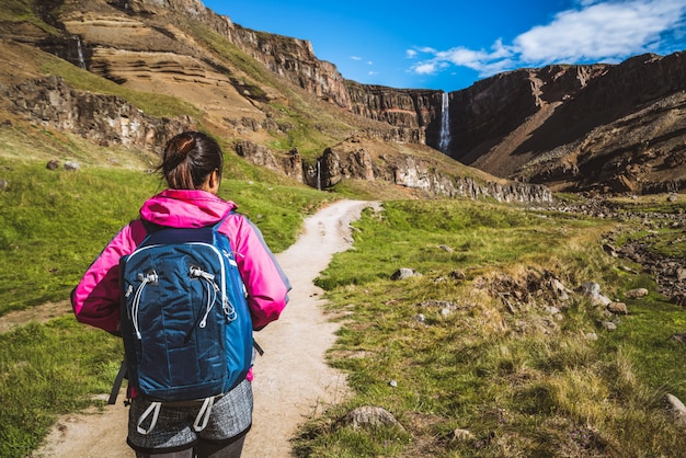 Traveler hiking at Hengifoss Waterfall, Iceland.