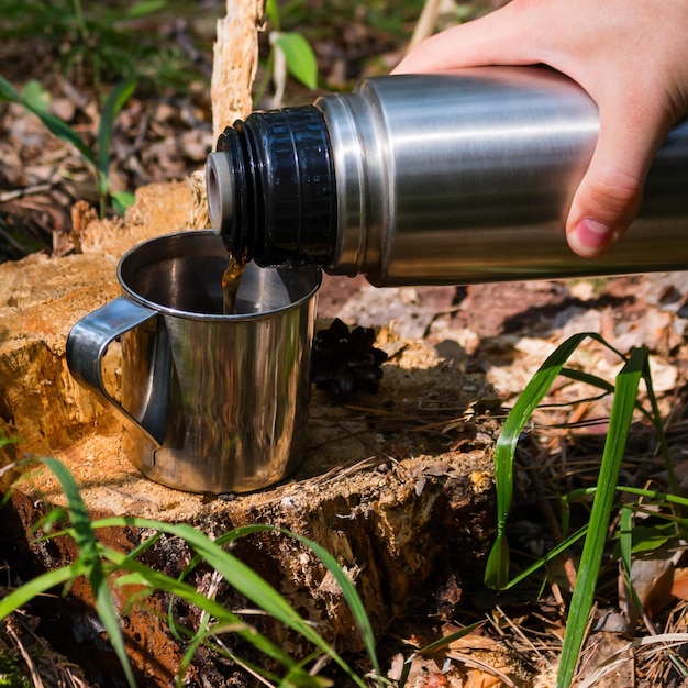 Traveler man pours tea from thermos outdoor