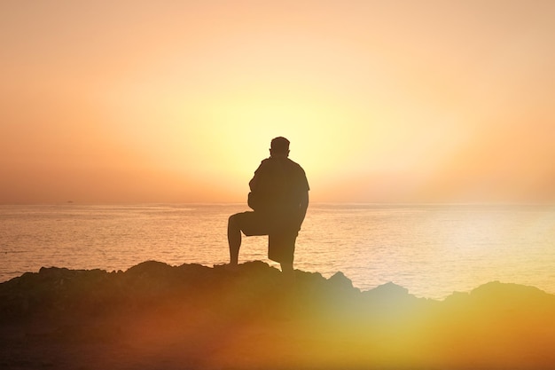 Traveler man silhouette at sunset on sea.