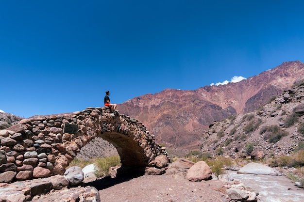 Traveler man sitting on picheuta bridge looking at the mountains