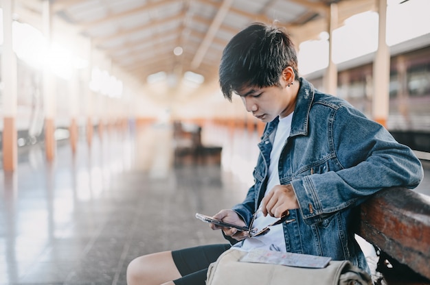 Traveler man using mobile phone on train station.