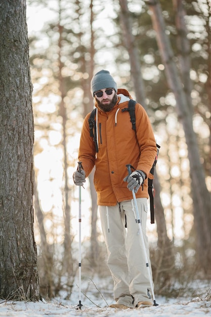 Traveler Man with backpack hiking in winter snowy forest landscape Travel Lifestyle concept adventure active vacations outdoor cold weather into the wild