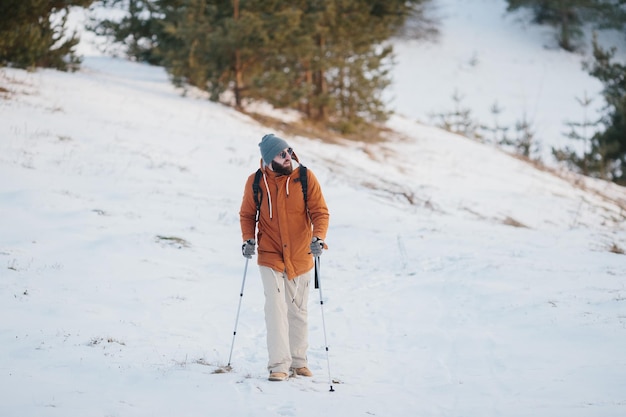 Traveler Man with backpack hiking in winter snowy forest landscape Travel Lifestyle concept adventure active vacations outdoor cold weather into the wild