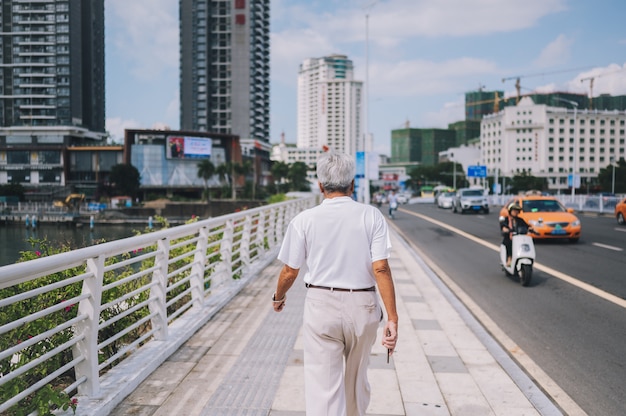 Traveler senior elderly man  walking in Asian city downtown with skyscrapers. Travel adventure nature in China, Tourist beautiful destination Asia, Summer holiday vacation journey trip concept