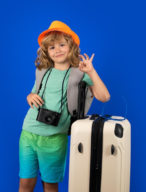 Traveler tourist kid boy 78 years old on isolated studio background Travel on weekends getaway Independent kid boy with big travel bag