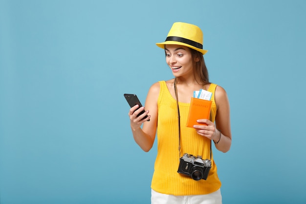 Traveler tourist woman in yellow casual clothes hat holding tickets cellphone camera on blue