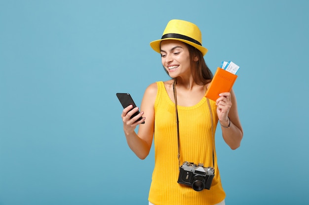 Traveler tourist woman in yellow casual clothes hat holding tickets cellphone camera on blue