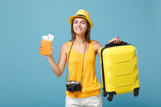 Traveler tourist woman in yellow summer casual clothes hat holding tickets bag camera on blue