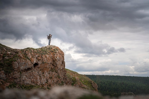 A traveler travel photographer on top of a mountain photographs nature landscape Landscape photography against the sky copy space