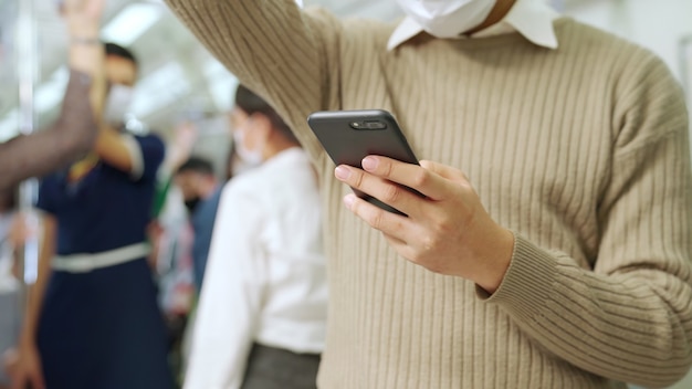 Traveler wearing face mask while using mobile phone on public train