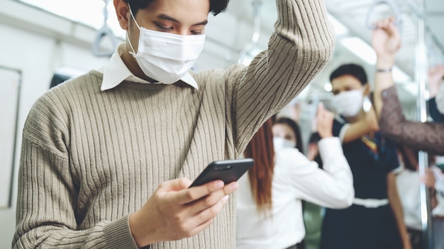 Traveler wearing face mask while using mobile phone on public train