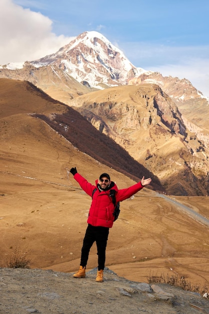 Traveler with backpack hiking alone in mountainous region backpacker walking down hillside road with...