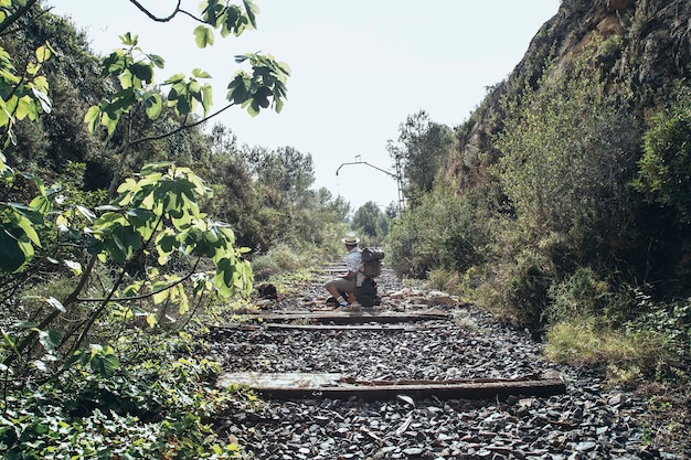 Traveler with a backpack in the middle of the abandoned train tracks