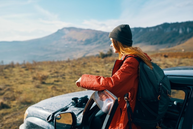 Traveler with a backpack near the car in the mountains in summer and blue sky fresh air