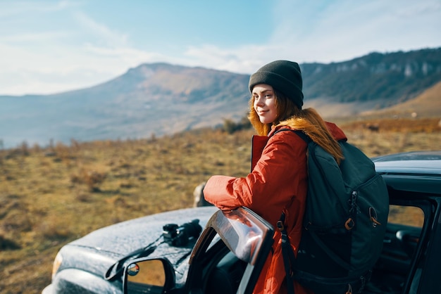 Traveler with a backpack near the car in the mountains in summer and blue sky fresh air