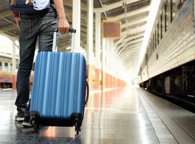 Traveler with a blue suitcase is waiting for the train.