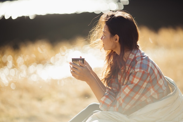 Traveler woman hiking in the mountains with cup of coffee near the lake