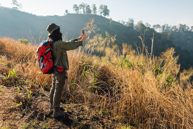 Traveler woman makes photo with smartphone on mountain view