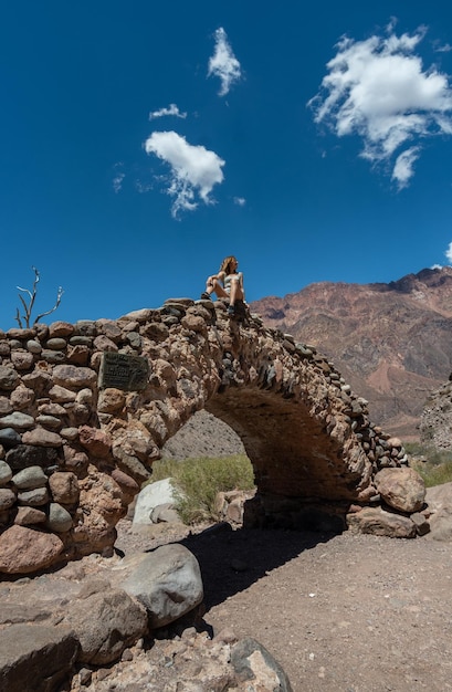 Traveler woman sitting on picheuta bridge looking at the mountains