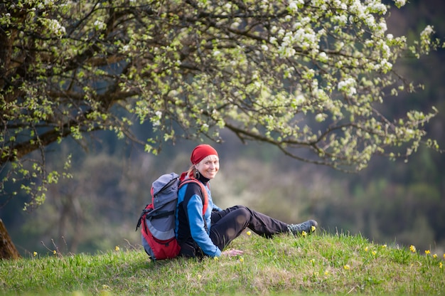 Traveler woman with a backpack near blooming tree