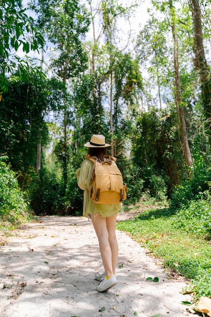 Traveler woman with backpack walking on path in jungle tropical forest Tourism beautiful destination resort Vertical shot