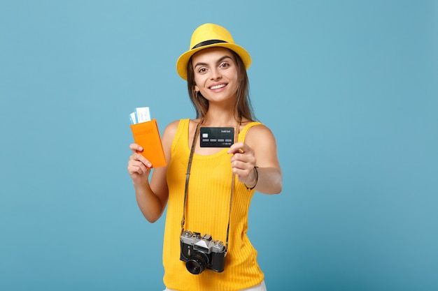 Traveler woman in yellow clothes hat holding tickets credit card camera on blue