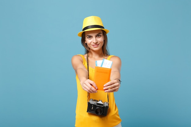 Traveler woman in yellow summer casual clothes and hat holding tickets camera on blue