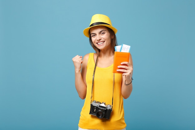 Traveler woman in yellow summer casual clothes and hat holding tickets camera on blue