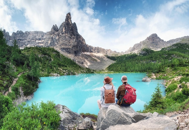 Travelers couple look at the mountain lake Travel and active life concept with team Adventure and travel in the mountains region in Dolomite alps Italy