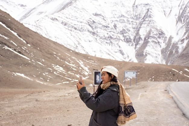 Travelers thai woman travel visit and posing for take photo with landscape high range mountain on Srinagar Leh Ladakh highway at Leh Ladakh village in Jammu and Kashmir India at winter season