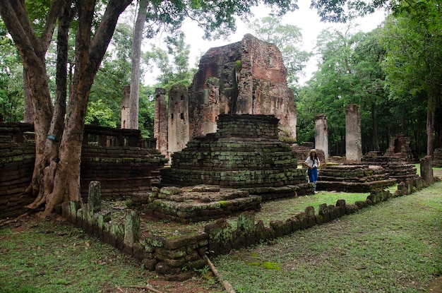 Travelers thai woman walking visit and travel take photo in ancient building and ruins of Kamphaeng Phet Historical Park is an archeological site and Aranyik Area in Kamphaeng Phet Thailand