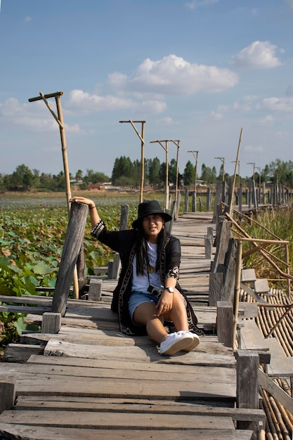 Travelers thai women people travel visit and posing portrait for take photo at Kae Dam long wood bridge at rural on January 11 2019 in Maha Sarakham Thailand