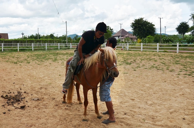 Travelers young thai men riding pony dwarf horse or Miniature horse walking in stable box stall animal farm of activity resort at Kaeng Krachan National Park on July 9 2011 in Phetchaburi Thailand