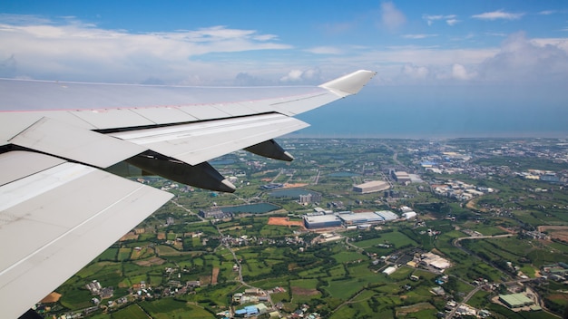 Traveling by air. Aerial view of a city at Taiwan Island. See the wing of the plane and the Taoyuan city in background as seen through an airplane window during the flight.