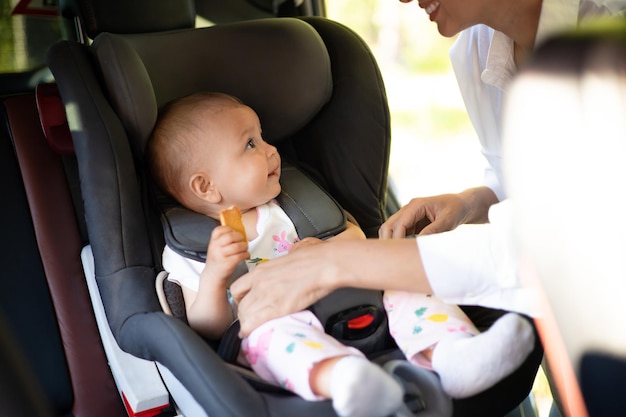 Traveling by car A child in a car seat Mom fastens the baby with seat belts Holidays with children