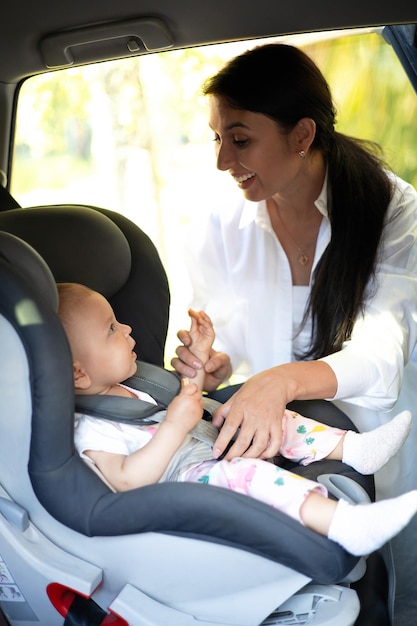 Traveling by car A child in a car seat Mom fastens the baby with seat belts Holidays with children