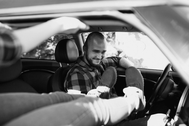 Traveling by car of a young couple of a guy and a girl in plaid shirts