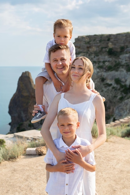 A traveling family holding hands and standing on top of a mountain at sunset